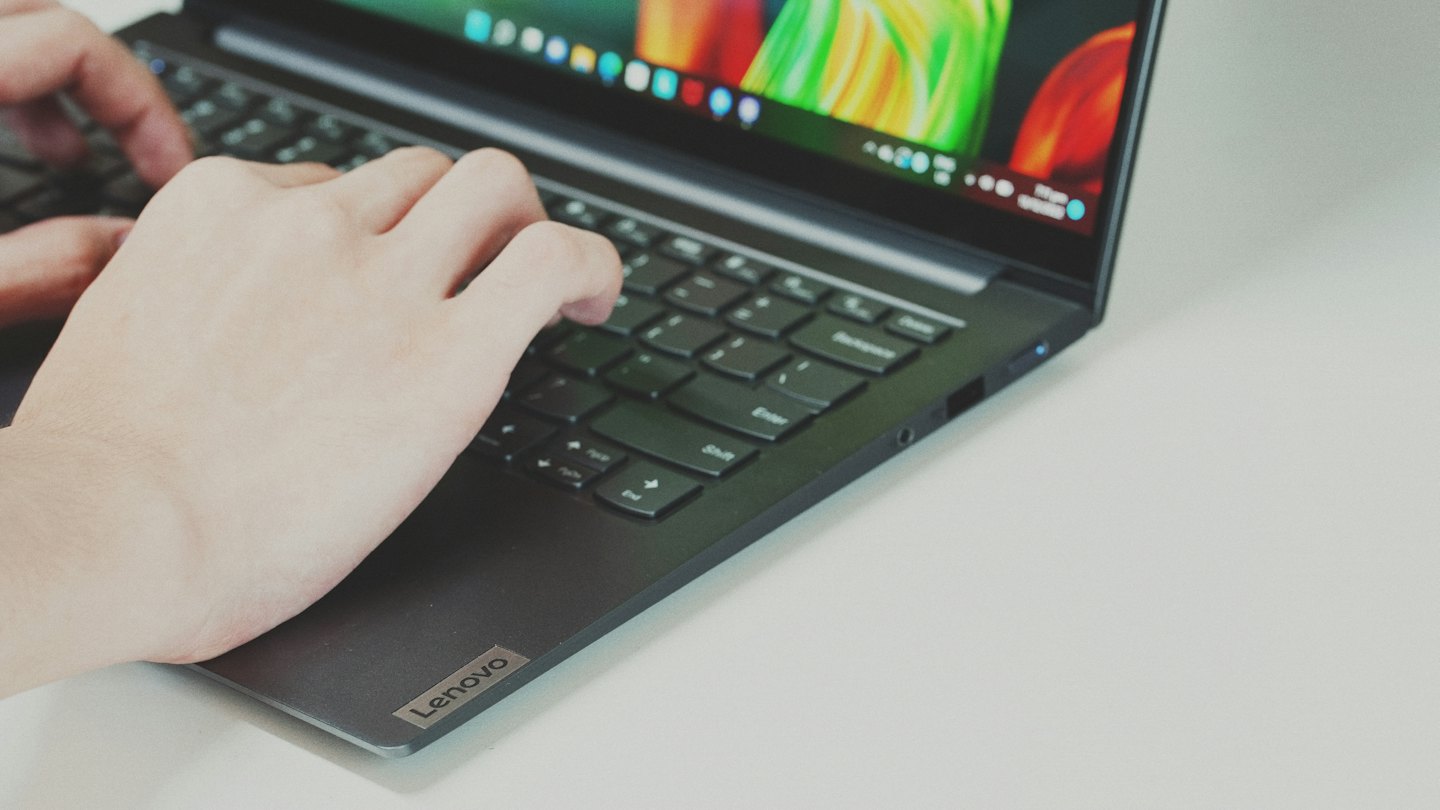 Hands typing on a dark grey laptop keyboard.